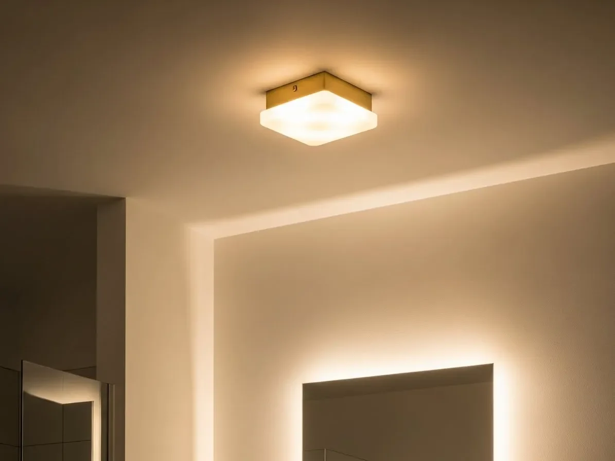 “Brass flush-mount ceiling light in a modern bathroom, glowing with warm ambient lighting for a cozy, upscale look.”